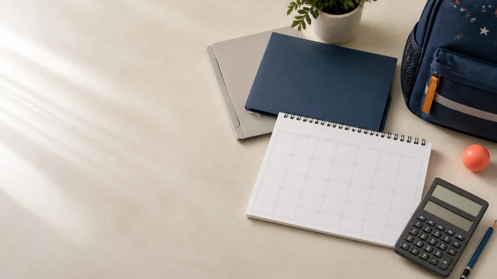 An organized calendar, folders, calculator, and child backpack on a quiet desk